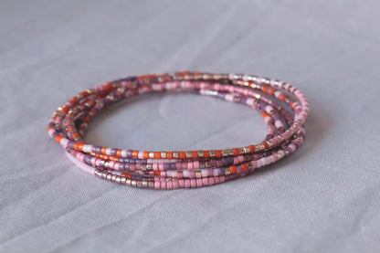 Bracelet Collier élastique en perles de verre rose et orange présenté sur fond gris