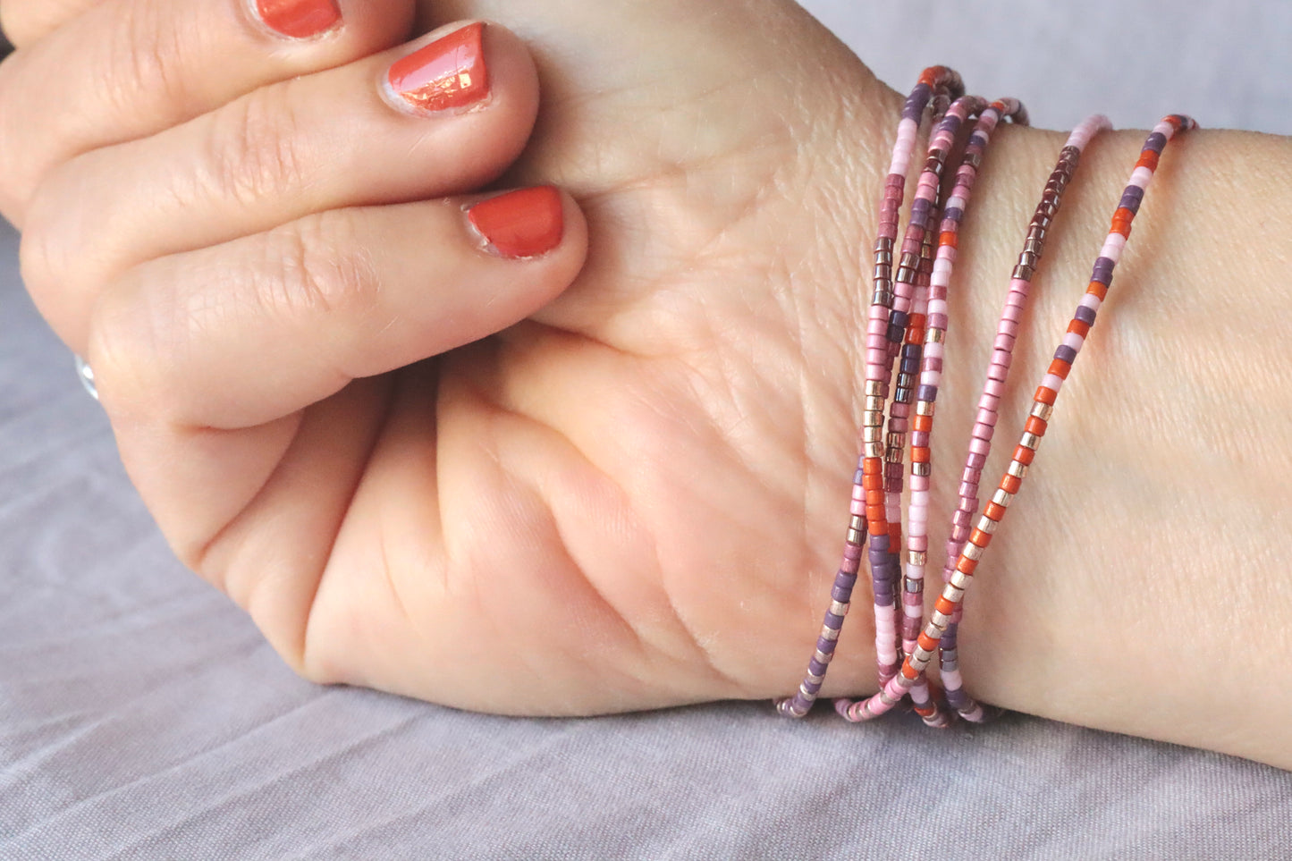 Bracelet élastique en perles de verre rose et orange sur poignet