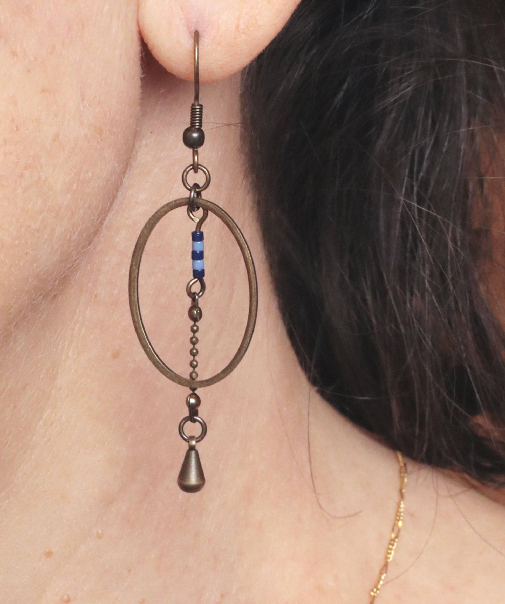 Gros plan des boucles d'oreilles pendantes, modèle Alana, portées à l'oreille